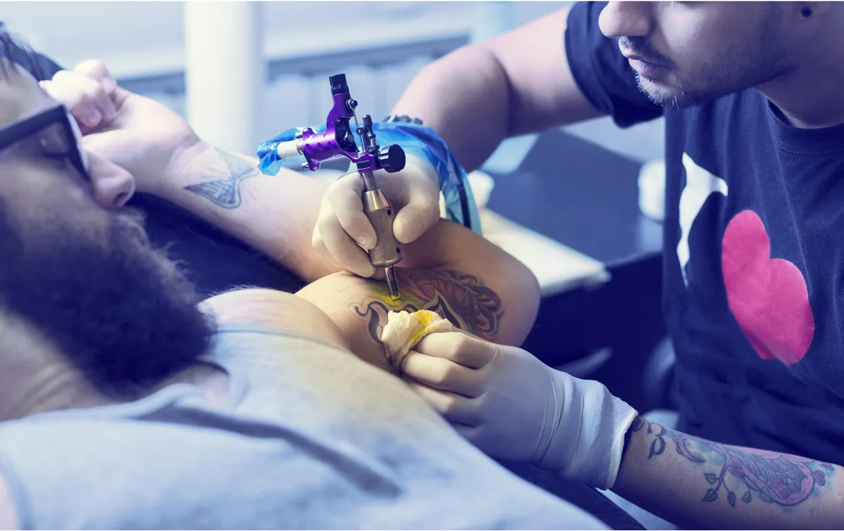 Männliche Person bekommt ein Tatto im linken inneren Oberarm