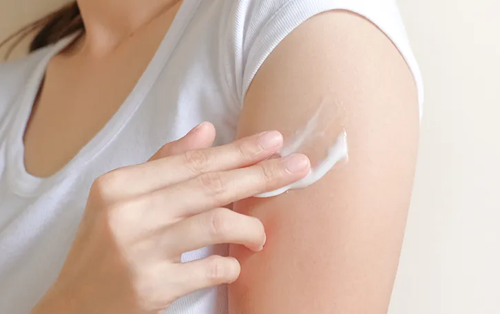 Lokale Hautbetäubung Betäubungscreme Creme unter Fingern auf einem Oberarm einer weiblichen Person